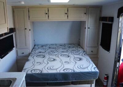 murphy bed brought down, near the entrance, with built-in shelving around the bed for the 21' comfort camper.